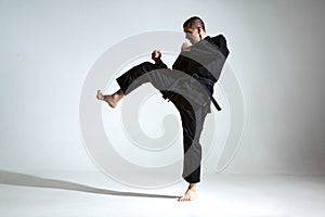 Fighting guy in black kimono fighter shows jiu jitsu technique on studio background with blank space, mix fight concept
