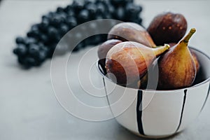 Figs in a bowl and dark grapes on a gray background. Autumn harvest