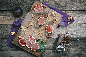 Figs, nuts and bread with jam on choppingboard in rustic style