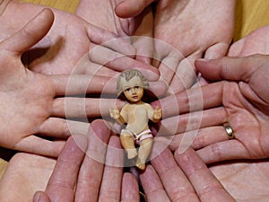 Figure of baby jesus liyng on hands of a family and wedding ring