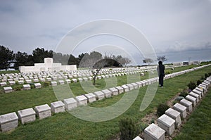 Figure in black reading gravestones, Gallipoli