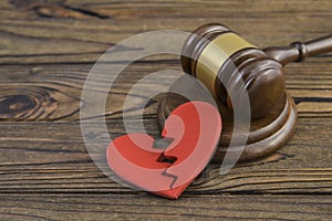 figure of a broken red heart, gavel, hammer of a judge on a wooden background