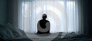 The figure in contemplation sitting by the window in a serene atmosphere. AI generated image