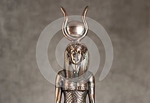 The figure of the Egyptian goddess Isis on a brown corduroy background. Bronze statuette