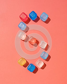 Figure five pattern from colored plastic ice cubes on a background in a color of the year 2019 Living Coral Pantone