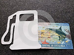 figure of gasoline pump in white and Costa Rican banknote of 2000 colones