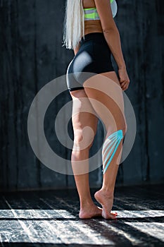 The figure of a girl athlete with a plaster for kinesiotherapy on the calf muscles