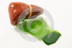Figure of human liver with gallbladder lies on white with seeping liquid with toxins after detox. Concept photo, symbolizing liver