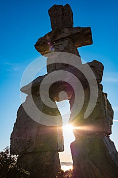 Figure of inukshuk on the seacoast against the sunset. Inukshuk at English Bay Beach in Vancouver BC