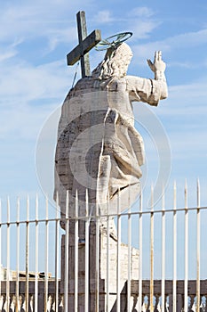 Figure of Jesus on the top of the facade of Saint Peter`s Basilica on a blue sky background, Vatican, Rome, Italy