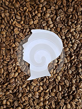 figure of a male human face of profile in white and background with roasted coffee beans
