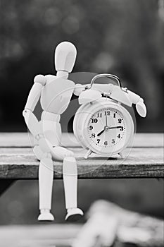 Figure of a man and an alarm clock. The concept of time, circadian rhythm, deadline. Black and white image, vertical orientation