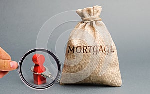 The figure of a man is handcuffed to a money bag with the word Mortgage. Impossibility of paying interest rates on mortgages and photo