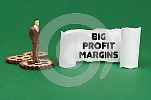 The figure of a man stands on the gears and reads the inscription - Big Profit Margins on paper