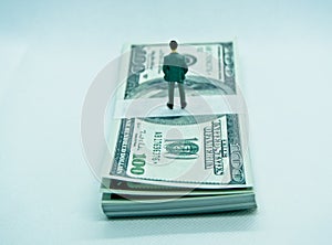 Figure of a man in a suit on top of a wad of dollar bills