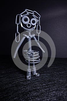 A figure of one small robot assembled from several bolts and nuts standing in a vertical position . It symbolizes technology,