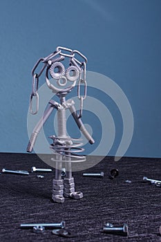 A figure of one small robot assembled from several bolts and nuts standing in a vertical position . It symbolizes technology,