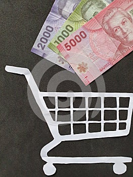 figure of a shopping cart on white paper and Chilean money