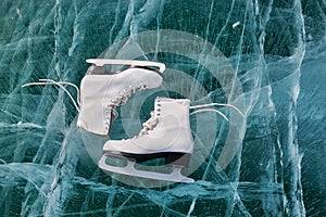 Figure skates at transparent cracked ice surface close up. Winter sport concept. Lake Baikal