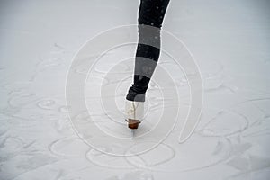 Figure skating on the street at an outdoor ice rink. Close-up of the skater`s legs on ice. A woman goes in for sports.