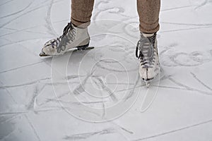 Figure skating on the street at an outdoor ice rink. Close-up of the skater`s legs on ice. A woman goes in for sports.