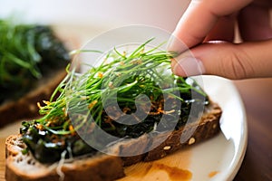 figure spooning seaweed salad onto toast