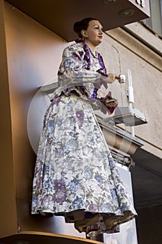 Figure of woman in beautiful dress with a cup of tee or coffe welcome guests. Doll on the wall of shop