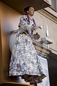 Figure of woman in beautiful dress with a cup of tee or coffe welcome guests. Doll on the wall of shop