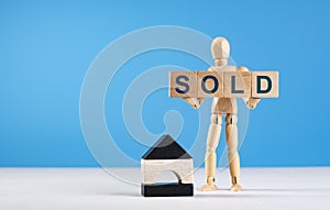 Figure of wooden man hold cubes with text sold. Property for sale