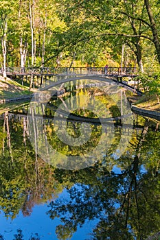 Figured bridge with patterns over a pond reflecting the sky and trees