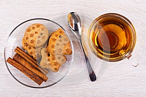 Figured cookies, cinnamon in saucer, tea in cup, spoon on table. Top view