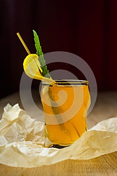 Figured glass of yellow fruit juice with a slice of lemon and gr