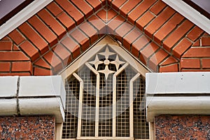 Figured lattice on building facade window under brick roof