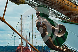 Figurehead of a boat in the shape of a green and gold Indian with a shield in his hand