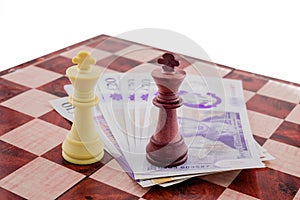 Figures of chess on chessboard and English money pounds