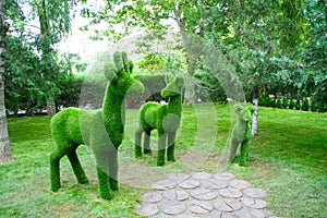 Figures of deer of different sizes in profile made of artificial fur green in the Park.