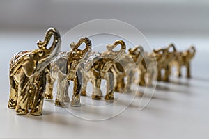 Figures of gilded elephants stand in a row in height. Selective focus