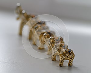 Figures of gilded elephants stand in a row in height. Selective focus