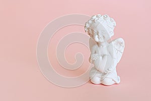 figurine of an angel Cupid with a bow on a pink background. Valentine's Day.