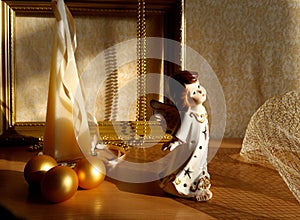 figurine of an angel, golden Christmas balls, pyramid candle on a textile background