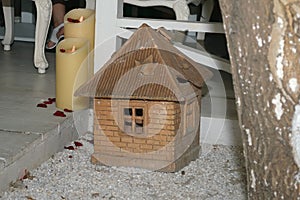 Figurine of a brick house stands on the ground near the festive table