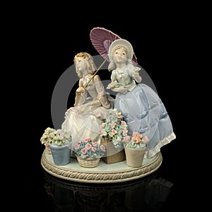 Figurine of children in puffy retro dresses on a black background.