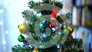 Figurine of a girl with a heart hanging on a branch of a Christmas tree among luminous garlands