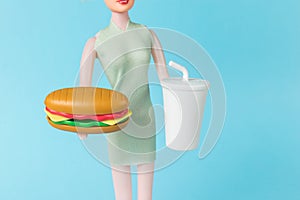 A figurine of a girl with a hot dog and a glass of drink on a blue background