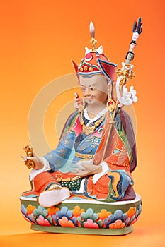 Figurine of Guru Rinpoche on an orange background. photo