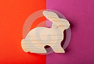 A figurine of a hare or a rabbit carved from solid pine by a hand jigsaw. On a multi-colored background