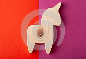 A figurine of a horse or unicorn carved from solid pine with a hand jigsaw. On a multi-colored background