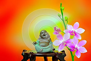 Figurine of laughing buddha decorated with pink orchid flowers