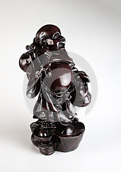 Figurine of a laughing Buddha on a white background. The title of a being who has achieved the highest state of spiritual