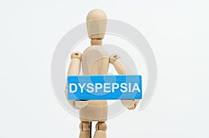 A figurine of a man holds in his hands a blue wooden block with the inscription DYSPEPSIA. The figurine is out of focus